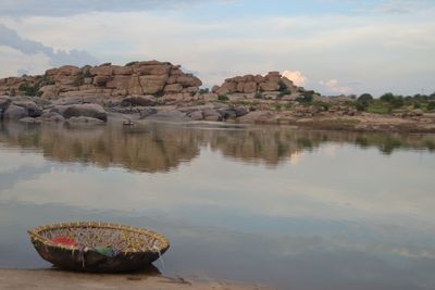 Rock formation by lake against sky