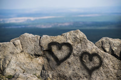 Close-up of heart shape on rock against sky