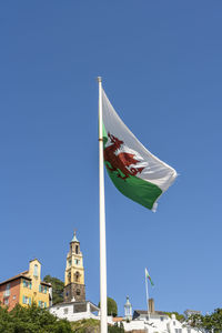 Low angle view of flags against clear blue sky