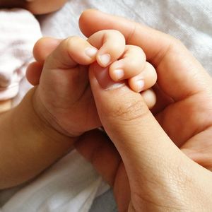 Low section of newborn baby holding father hand