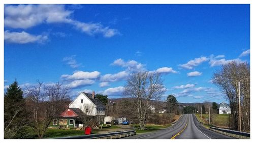 Road amidst buildings against blue sky