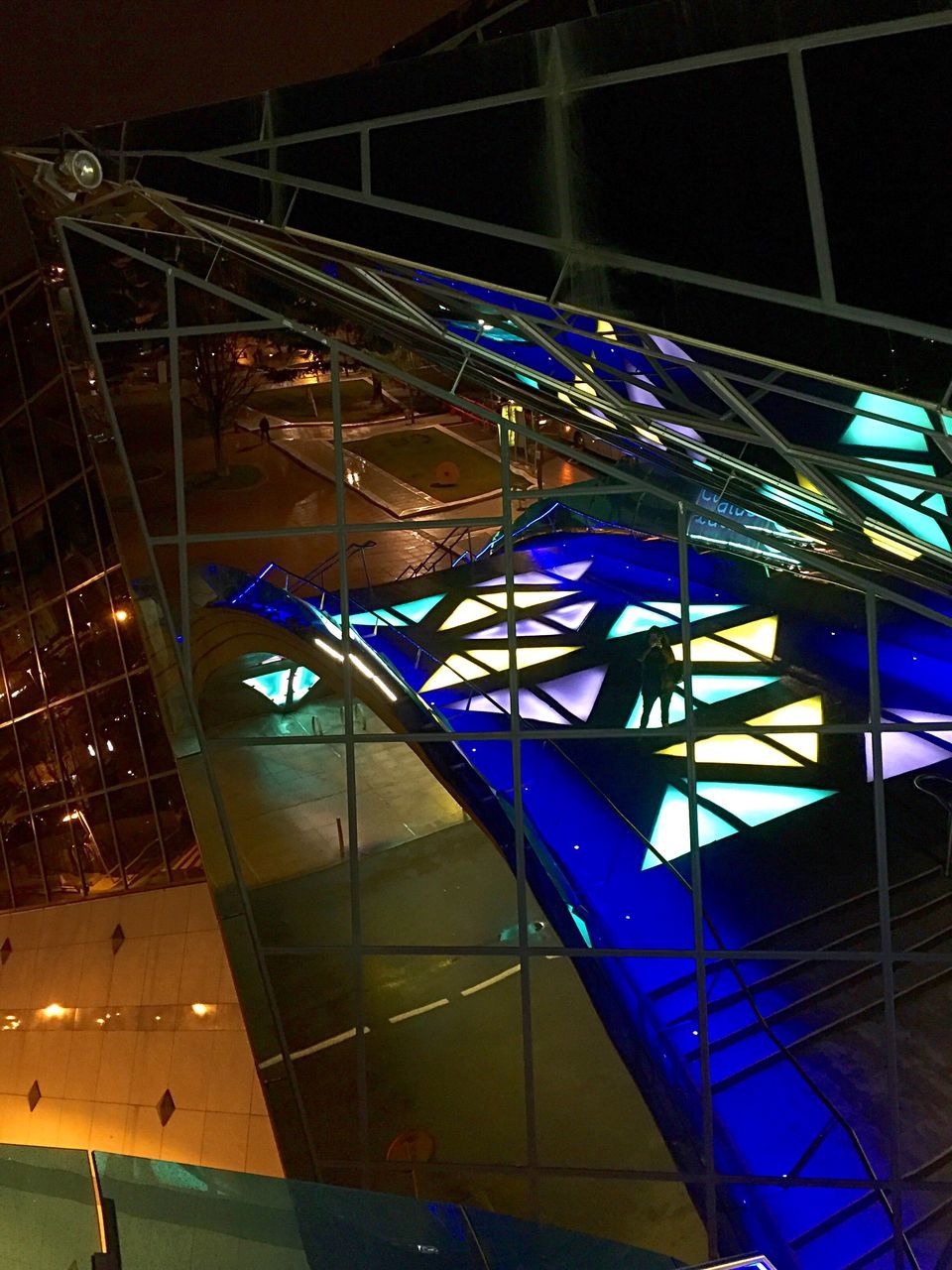 illuminated, night, built structure, architecture, arts culture and entertainment, amusement park, amusement park ride, multi colored, lighting equipment, blue, building exterior, low angle view, city, modern, indoors, metal, pattern, light - natural phenomenon, incidental people