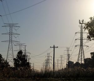 Low angle view of silhouette electricity pylon against clear sky