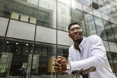 Thoughtful man with hands clasped in front of building