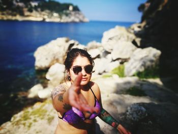 Close-up of woman wearing reaching towards camera at beach