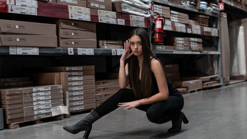 Full length portrait of young woman stretching on floor in warehouse