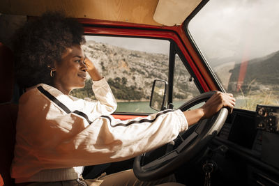 Side view of smiling young woman driving van during road trip