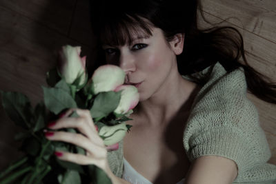 Portrait of mid adult woman with bouquet sitting at home