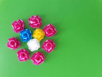 High angle view of multi colored artificial flower against green background