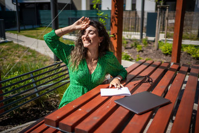 Young woman using mobile phone while sitting on table