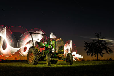 Illuminated traditional windmill on field against sky at night