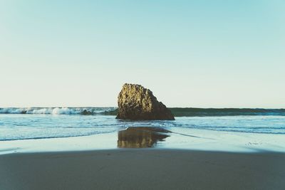 Rocks on beach against clear sky