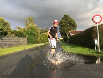 Full length portrait of boy splashing water while skateboarding on street