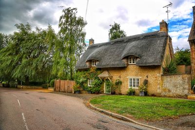 Road amidst trees and buildings against sky