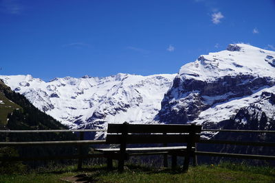 Snow covered bench against blue sky