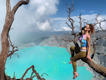 High angle woman wearing mask sitting by volcanic crater