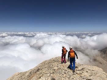 Rear view of men hiking on mountain against sky