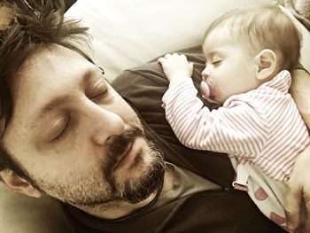 High angle view of baby girl and father sleeping at home