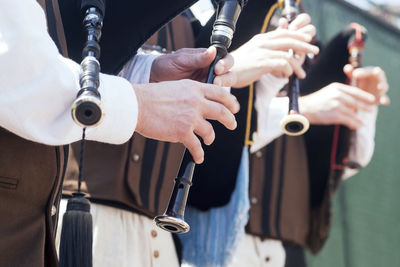 Midsection of men playing bagpipes 
