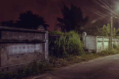 Abandoned house by road against sky at night