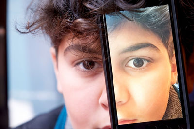 Close-up portrait of teenage boy with mobile phone