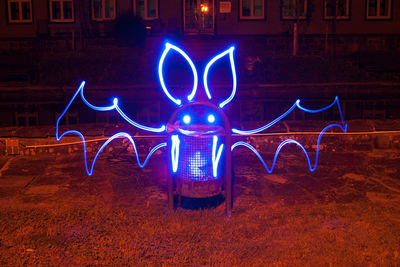 Light painting on garbage bin against house at night