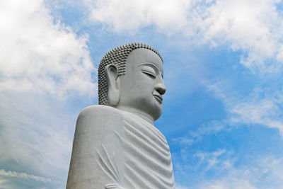 Low angle view of buddha statue against sky