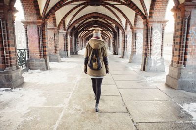 Rear view of young woman walking at railroad station platform during winter