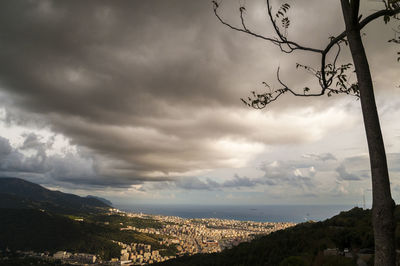 Aerial view of city by sea against cloudy sky