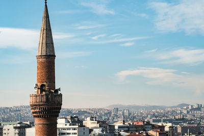 Mosque building in city against cloudy sky