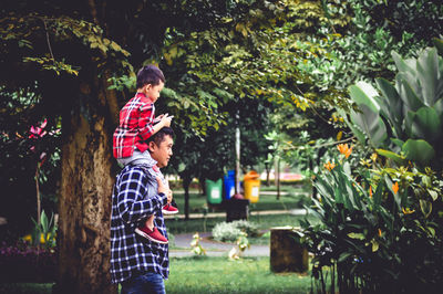 Rear view of father and son against trees