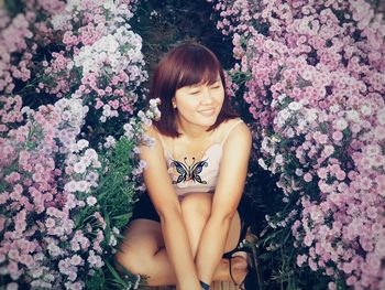 Full length of smiling woman sitting amidst plants