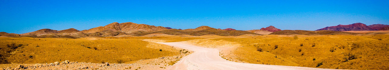Scenic view of desert against clear blue sky