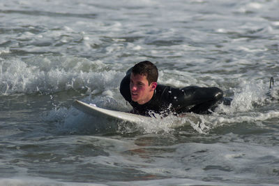 Young man surfing in sea