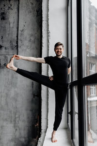 Portrait of young woman standing against wall