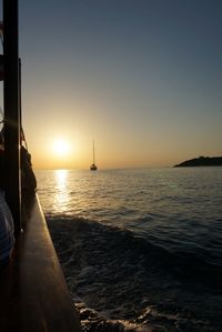 Sailboat sailing in sea at sunset