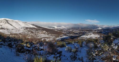 Scenic view of snowcapped mountains against blue sky