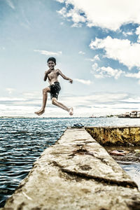 Full length of man jumping in sea against sky