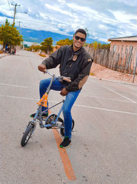 Young man riding motorcycle on road against sky