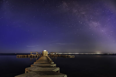 Pier over sea against sky at night