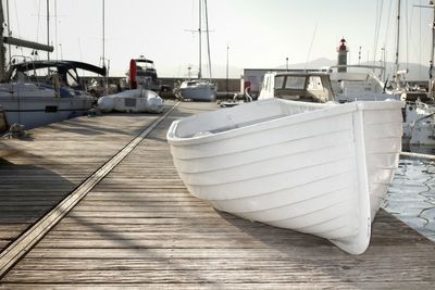 Boat on boardwalk against sky at harbor