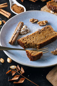 A sugar powdered slice of pumpkin sponge cake on a blue plate