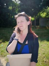 Portrait of teenage girl using mobile phone on field