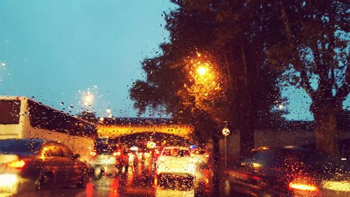 Illuminated road seen through wet window during rainy season