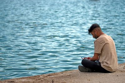 Rear view of man sitting on beach