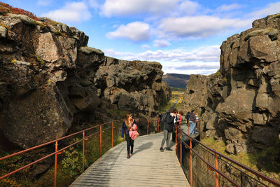 People walking on rocky mountain against sky