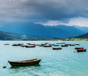 Boats in sea against cloudy sky