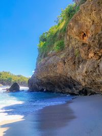 Rock formation on beach against clear blue sky