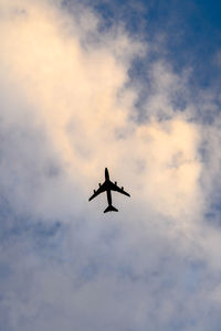 Low angle view of silhouette airplane flying against sky