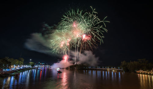 Firework display over river against sky at night